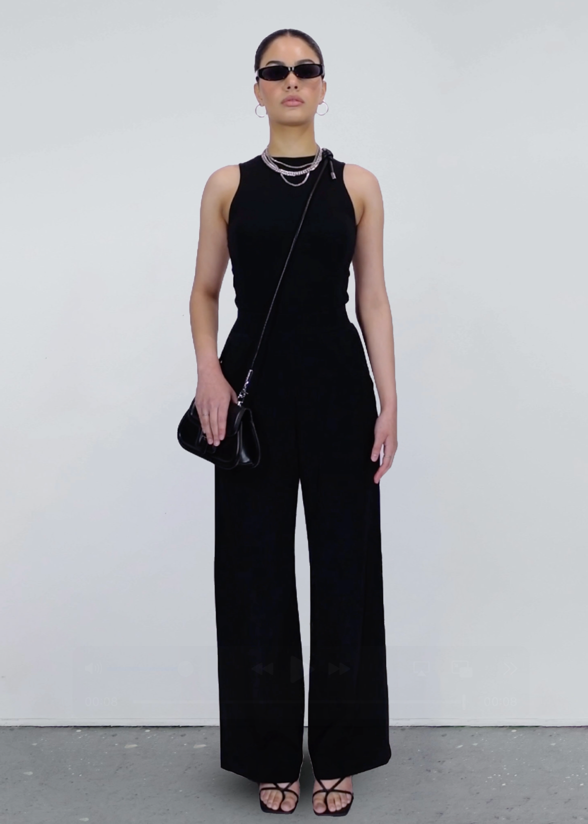 Woman wearing a black sleeveless 2 piece set that looks like a jumpsuit