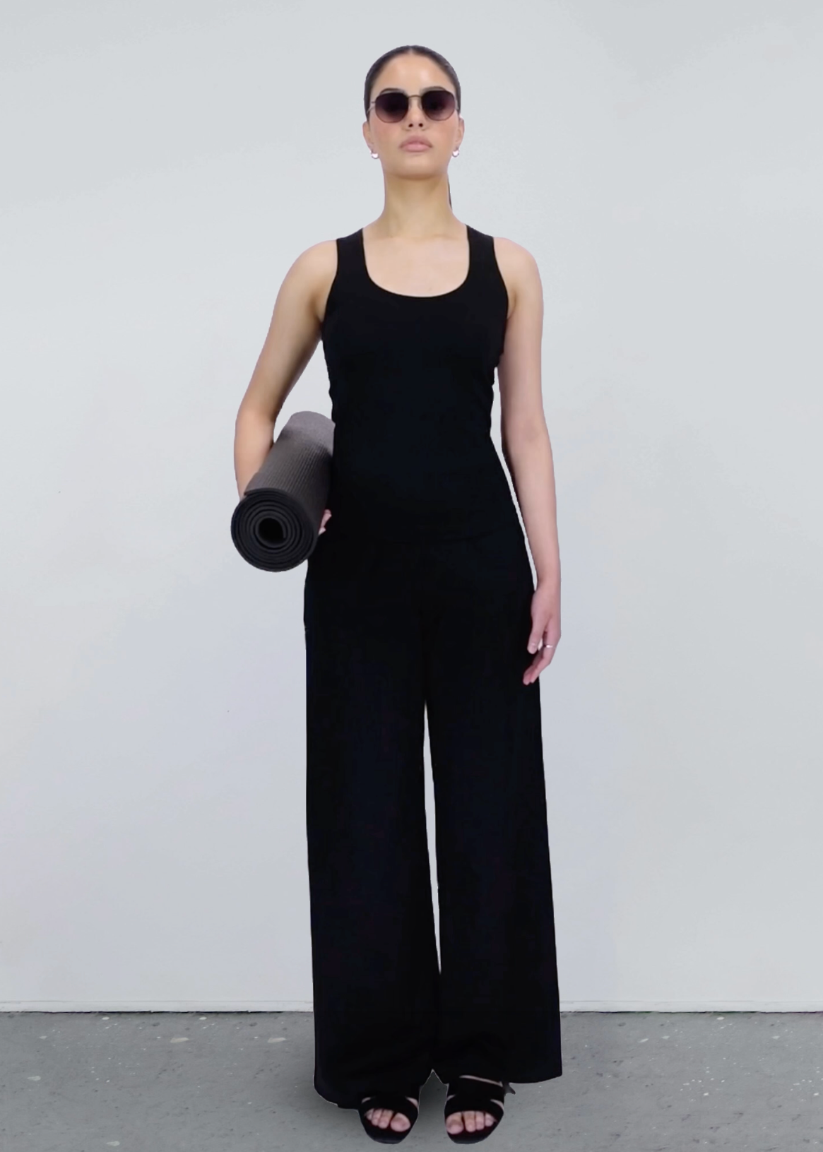 Person wearing a black outfit holding a yoga mat