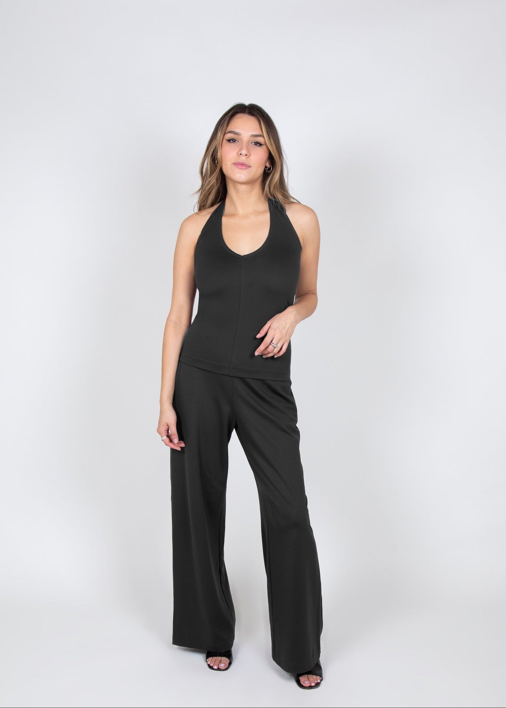 Woman wearing a dark grey halter and wide leg pants that looks like a jumpsuit