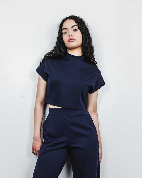 woman wearing mock neck cap sleeve top in navy with navy pants 