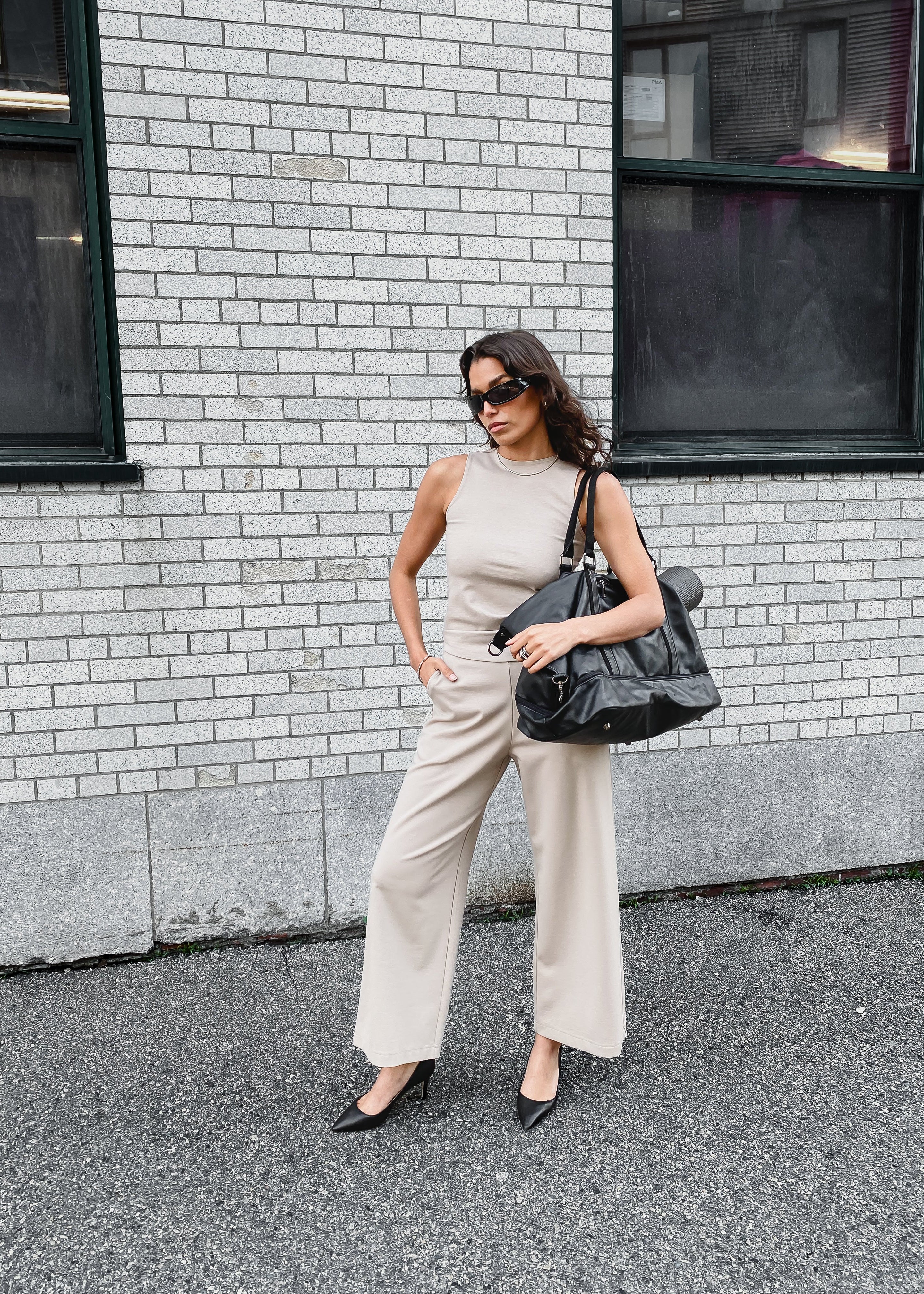taupe high neck sleeveless top and taupe wide-leg pants styles with travel duffle bag 